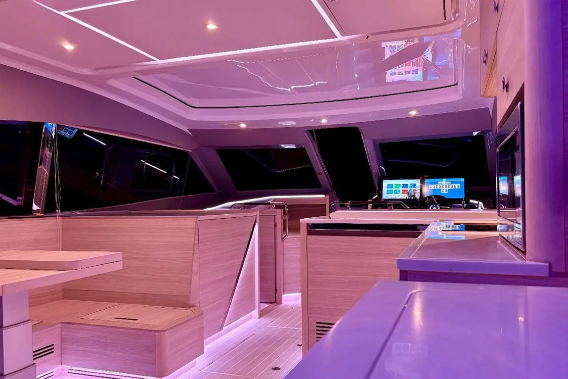 Modern yacht interior with sleek wood finishes, ambient lighting, and a control panel visible through large windows.